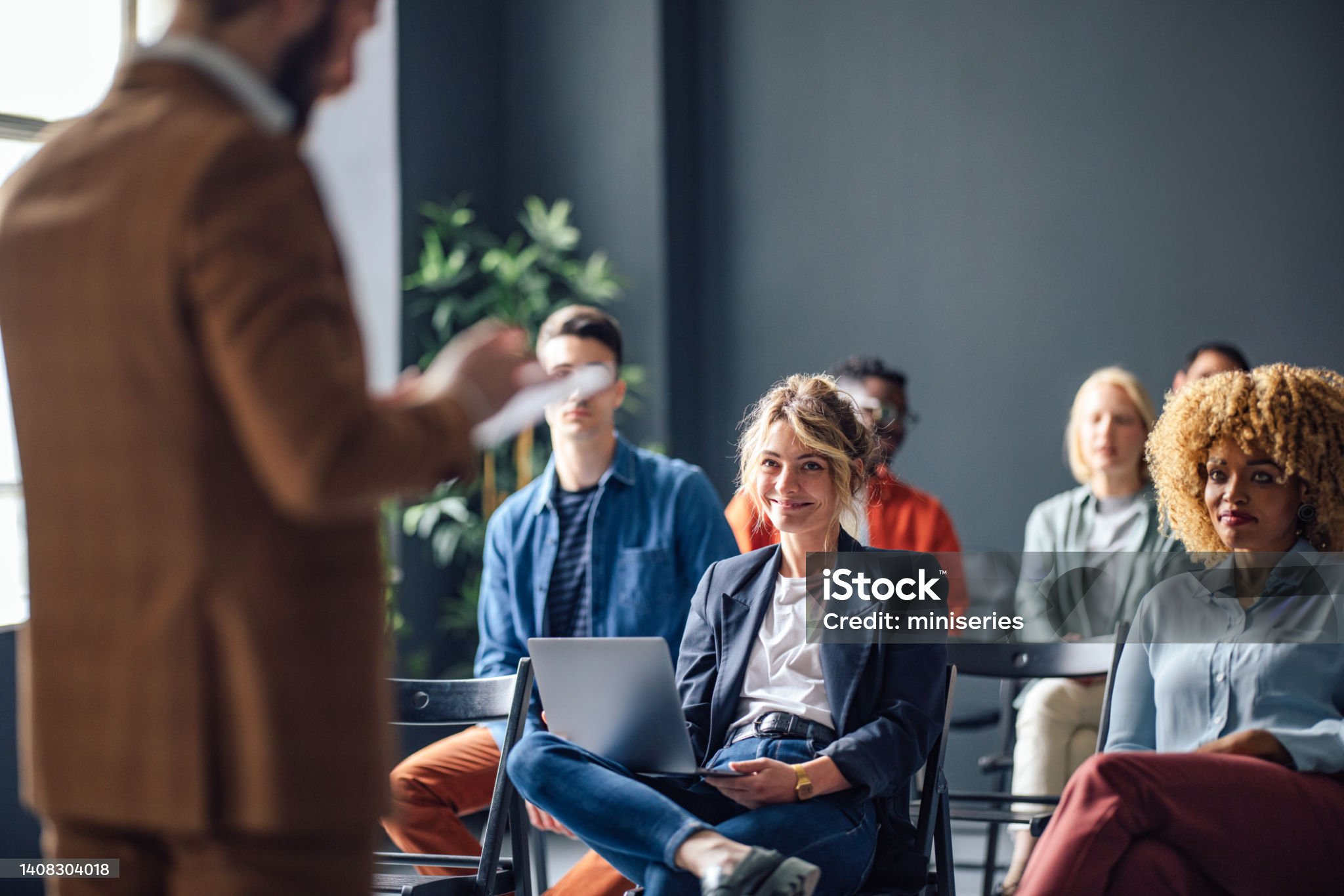 group of men and women sitting and listening to a seminar. they are smiling.